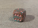 Decorative dice with a red and green pattern on a beige carpet