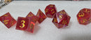Set of red polyhedral dice with gold numbers on a white surface