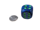 Blue die with green dots next to a silver coin on a gray surface